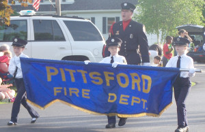 Pittsford youngsters carry the Pittsford Fire department banner onto the Mendon fire hall grounds. Photo by Donna MacKenzie